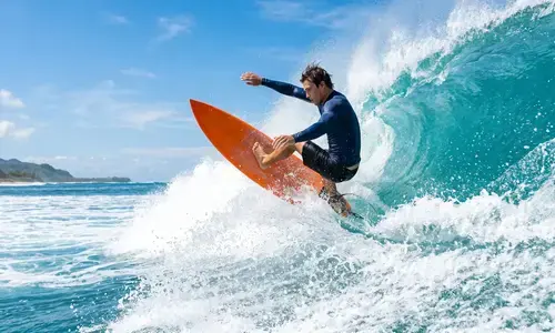 Surfer riding a wave on a surfboard at Lighthouse Beach Kovalam highlight of adventure sports in Kerala