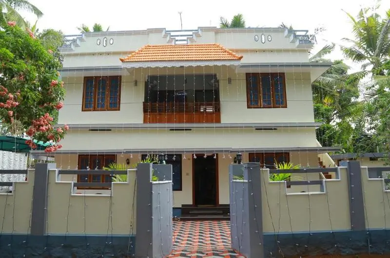 Multi-story modern white and cream building of Jeevan Homestay Kovalam with a front balcony porch and gated boundary wall.