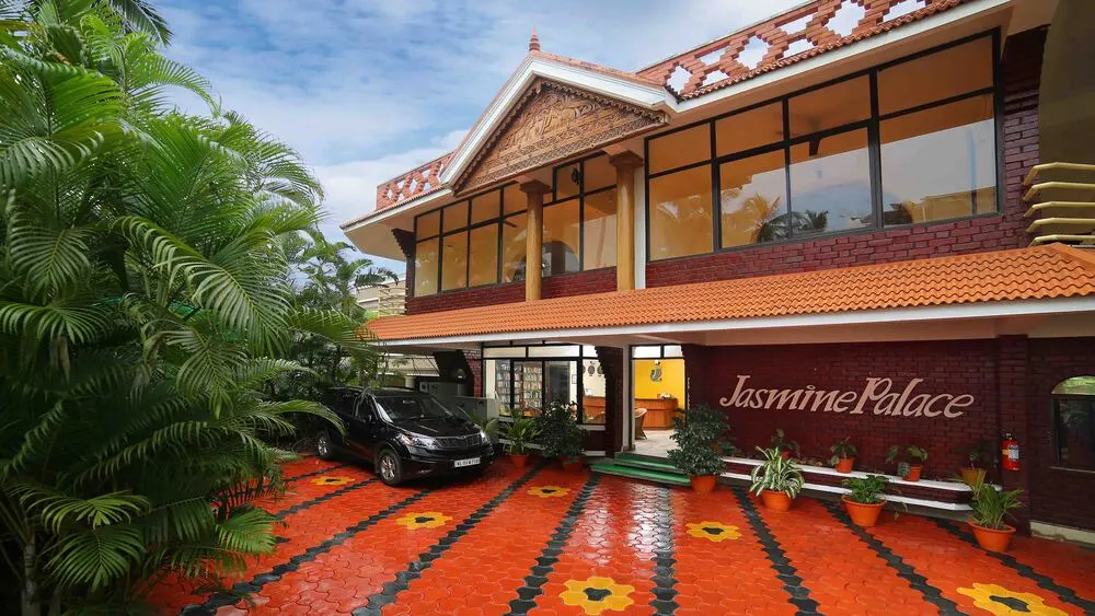 Multi-story building of Jasmine Palace Kovalam featuring traditional architecture and a patterned front courtyard.