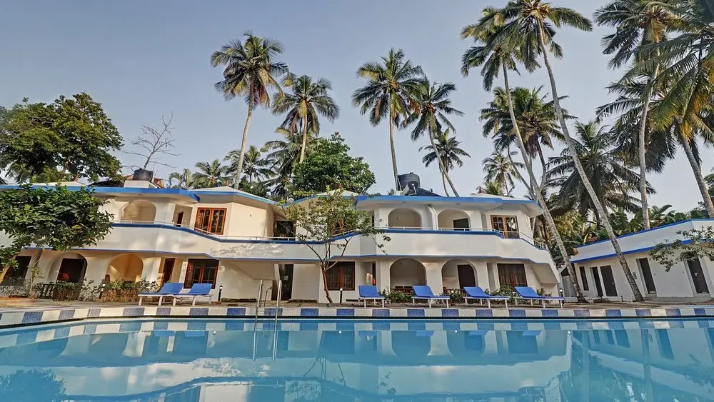 Treebo Trend Linchu Ayur Resort building exterior and swimming pool surrounded by palm trees in Kovalam