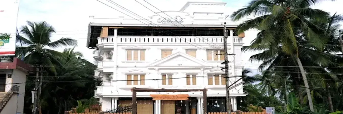La Promenade Hotel Kovalam white building exterior with guest balconies and tropical palm trees