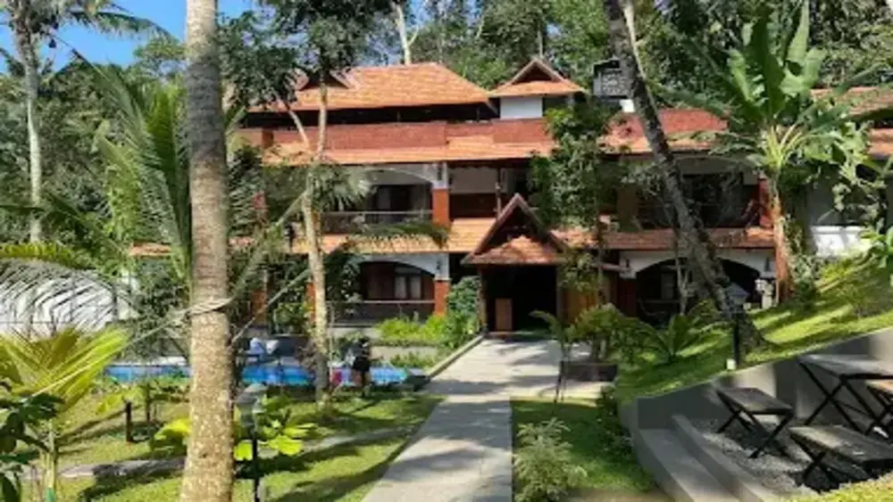 Traditional Kerala-style heritage building with terracotta tiled roofs and wooden balconies at Jeevan Homestay Chowara Kovalam