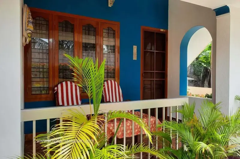 Close-up view of the bright blue exterior wall veranda and wooden chairs at Gokulam Homestay Kovalam