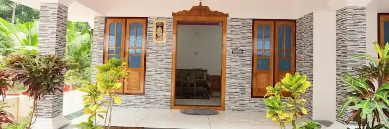 Traditional Kerala-style wood frame entrance and stone-accent verandas at Bougainvillea Homestay Kovalam