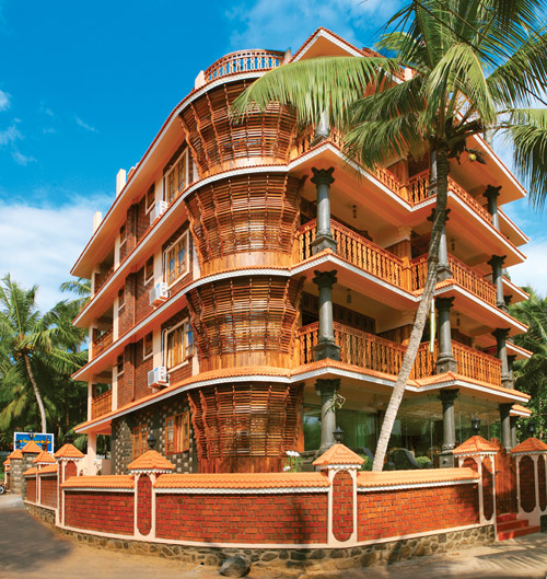 Multi-story brick facade architecture and balcony structure of Sun Tara Beach Resort Kovalam under a clear blue sky