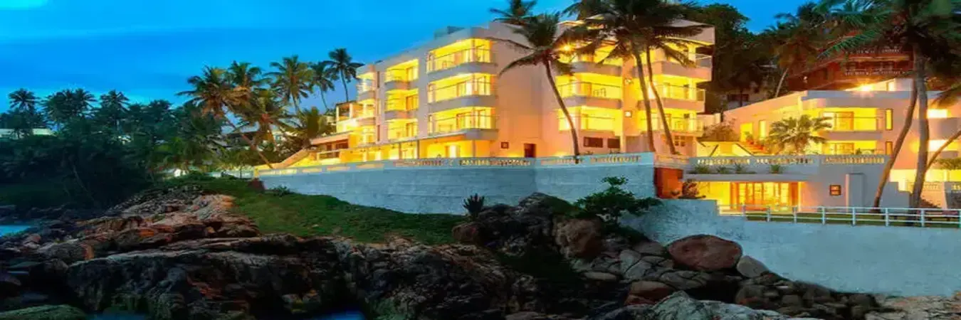 Rockholm beachfront hotel facade lit up at dusk in Kovalam