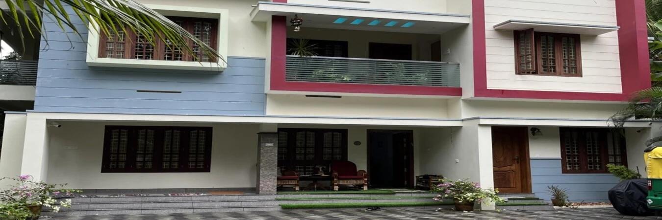 Wide angle perspective of the multi-story Laure's House Kovalam building with red and blue window borders