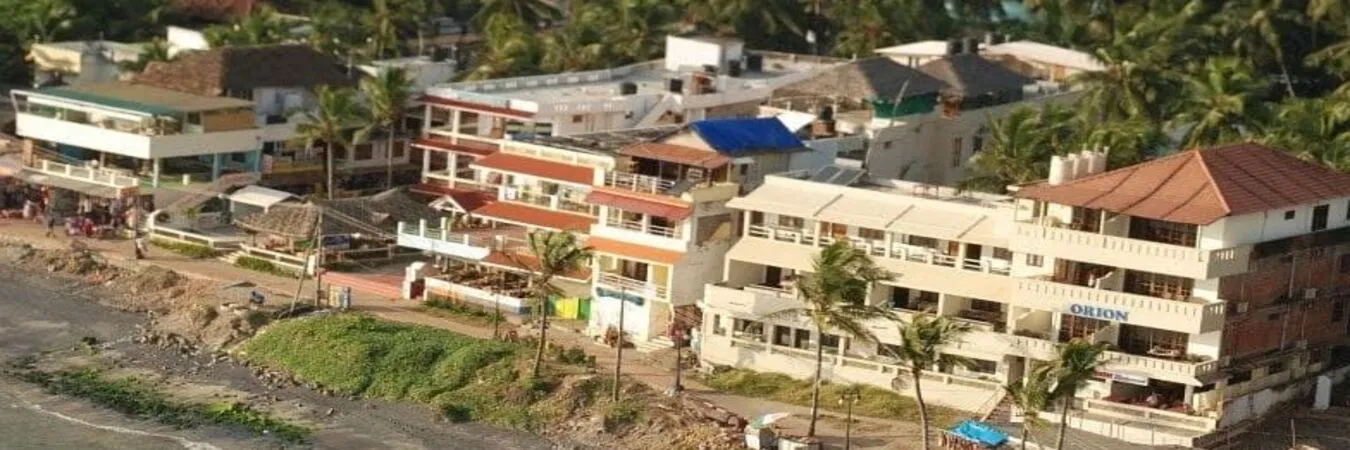 Elevated view of Orion Seaview Beach Resort surrounded by lush green coconut groves near Light House Road Kovalam