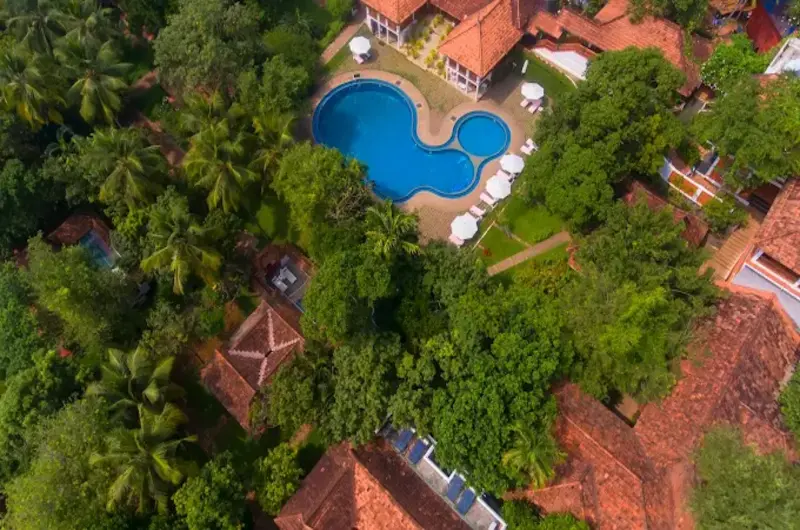 Aerial view of traditional heritage cottages and outdoor swimming pool at The Travancore Heritage Chowara