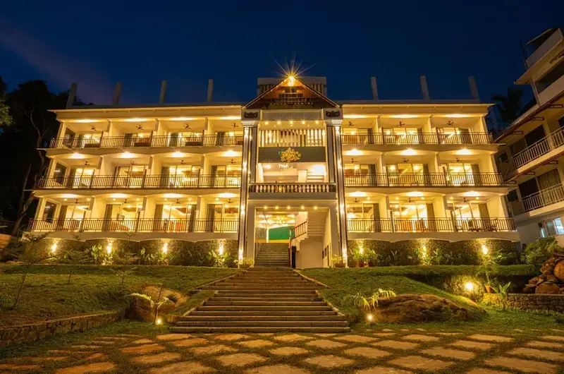 Multi-story building of Aadisaktthi Leisure Resort Kovalam illuminated with warm golden lights at night.
