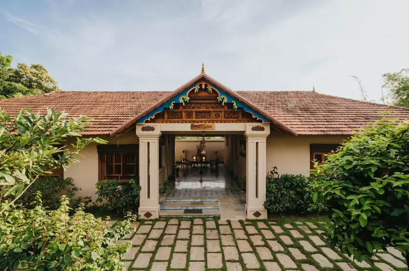 Traditional Kerala style cottage architecture and garden pathways at Aadisaktthi Leisure Resort.