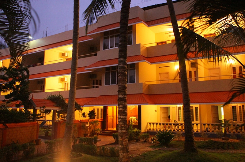 Multi-story building of Golden Sands Beach Resort Kovalam brilliantly illuminated with warm lights at night.