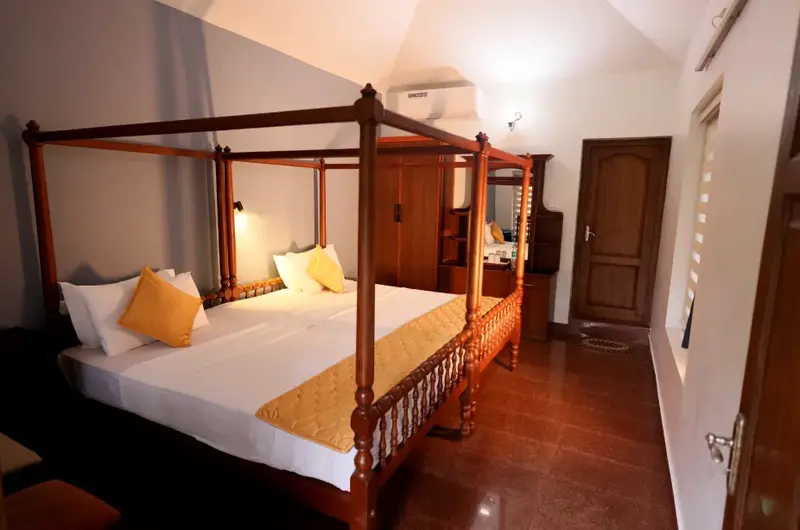 Luxury guest suite room featuring a traditional wooden four-poster bed at Ideal Ayurvedic Resort Kovalam.