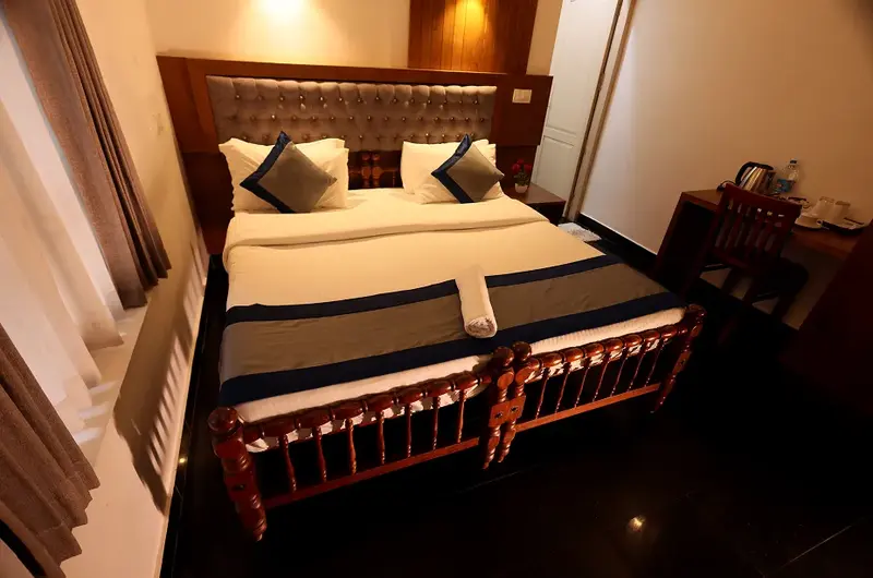 Large deluxe family room accommodation with elegant dark wood furnishings at Ideal Ayurvedic Resort.