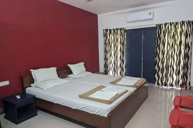 Clean air-conditioned double bedroom accommodation with modern wood paneling at Indeevaram Apartments Kovalam.