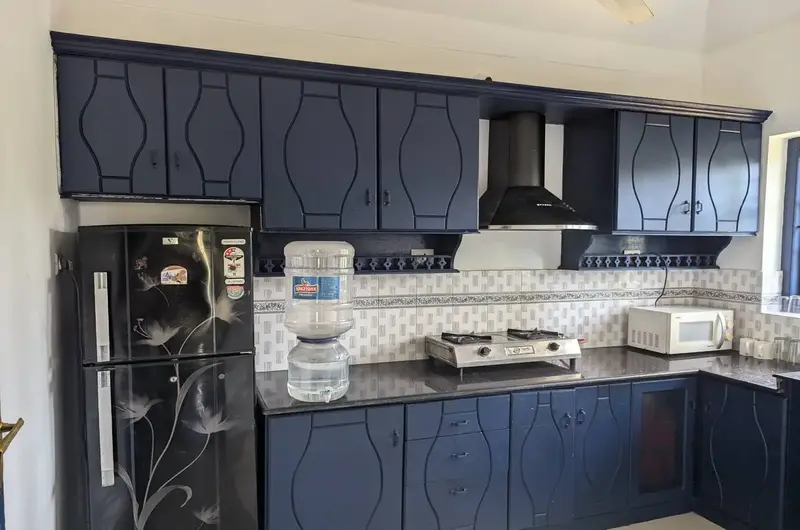 Modern self-catering kitchen counter and dark wood cabinets inside Indeevaram Apartments Kovalam.