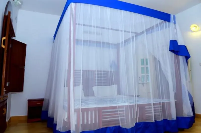 Standard double bedroom featuring a traditional mosquito net at Little Elephant Beach Resort Kovalam