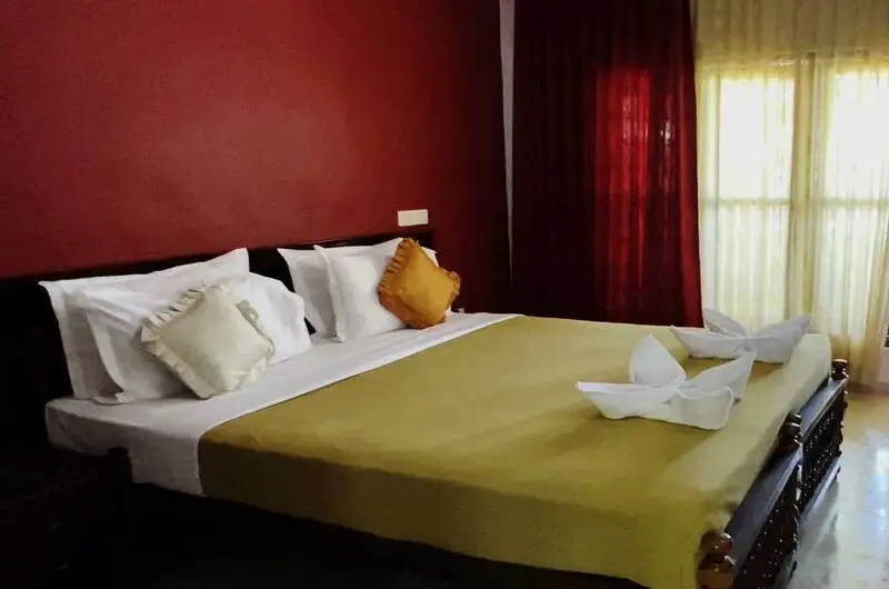 Deluxe AC double bedroom featuring a vibrant red accent wall at Pappukutty Beach Resort Kovalam