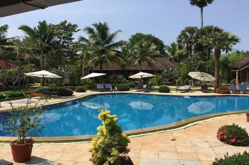 Poolside sun loungers and outdoor swimming pool facility at Poovar Island Resort
