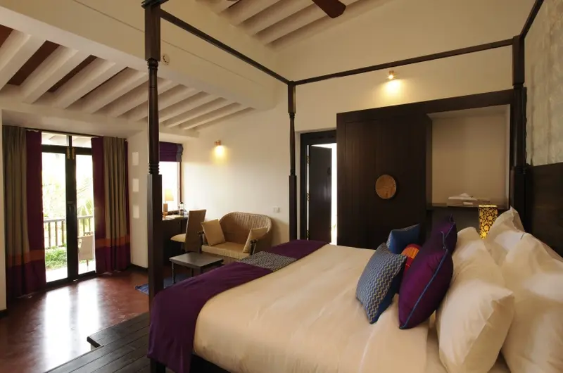 Premium heritage suite bedroom featuring a traditional wooden ceiling at Niraamaya Retreats Surya Samudra