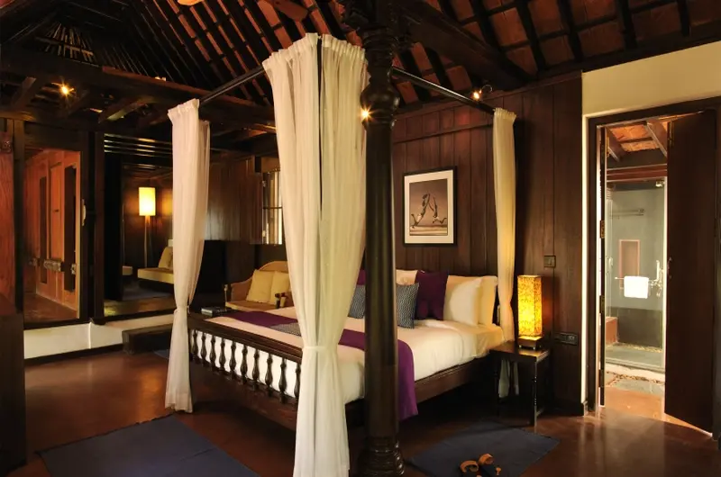 Luxury heritage suite featuring a traditional four poster bed and wooden architecture at Niraamaya Retreats Surya Samudra Kovalam