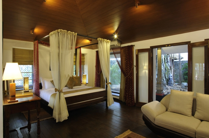 Premium cottage bedroom with large open doors and garden views at Niraamaya Retreats Surya Samudra