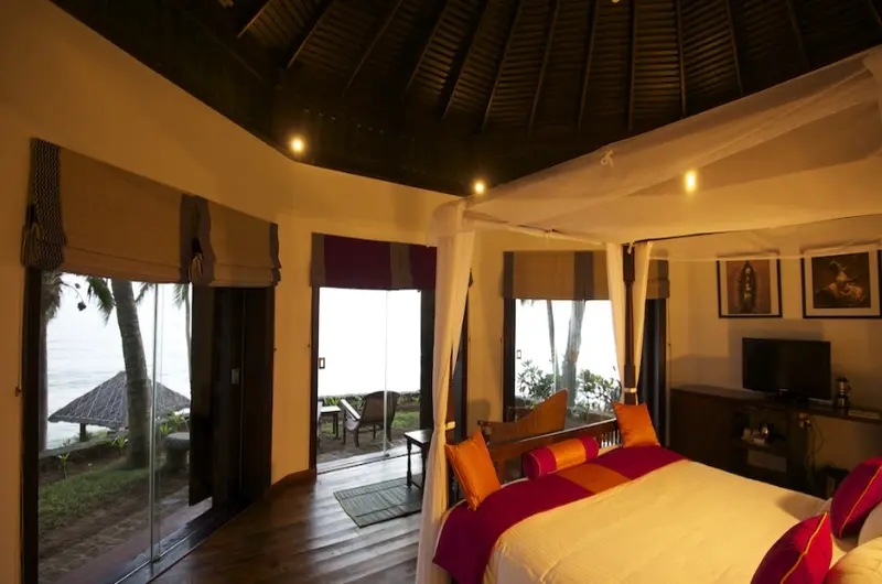 Cozy deluxe heritage room interior with warm ambient lighting at Niraamaya Retreats Surya Samudra Kovalam