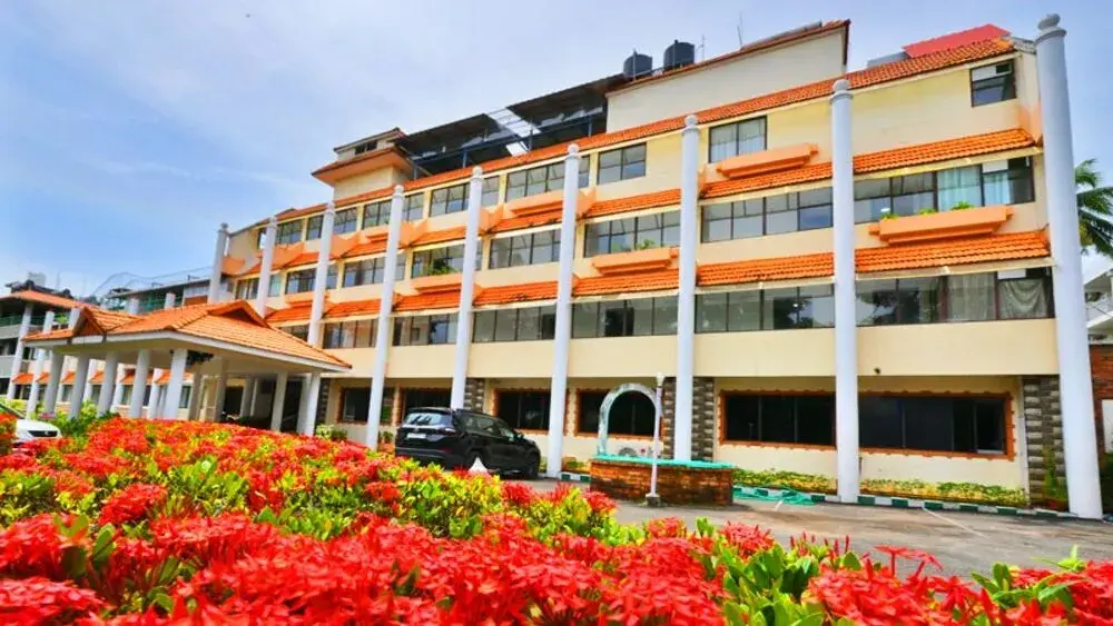 Multi story resort building facade and vibrant flower gardens at Swagath Holiday Resort Kovalam