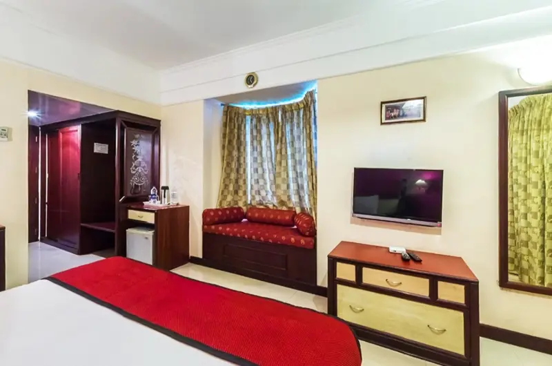 Spacious deluxe double bedroom with modern furniture and television setup at Swagath Holiday Resort Kovalam