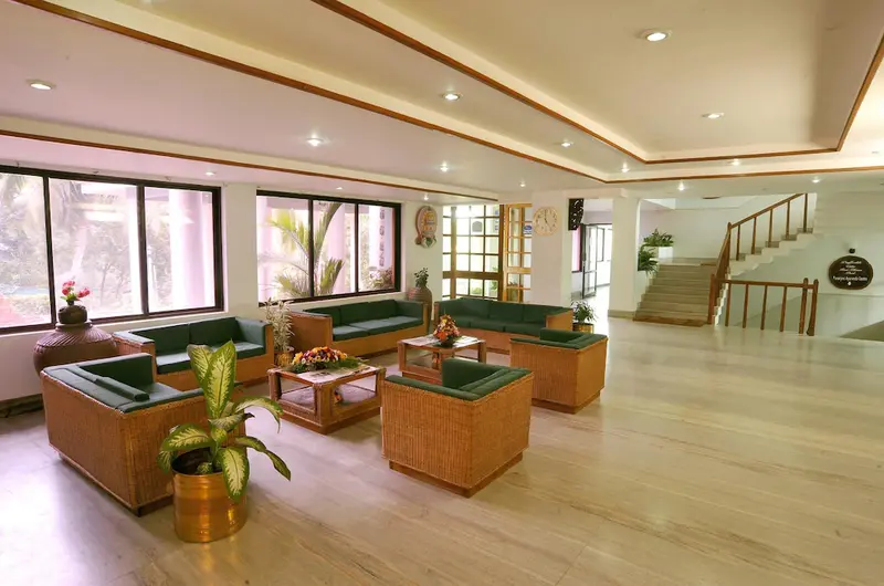 Bright indoor guest lounge and seating area with large glass windows at Swagath Holiday Resort