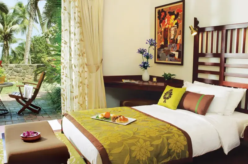 Luxury resort bedroom interior with large window facing tropical gardens at Taj Green Cove Resort