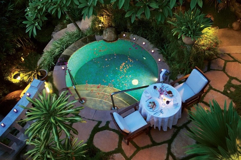 Illuminated outdoor private plunge pool surrounded by palm trees at Taj Green Cove Resort