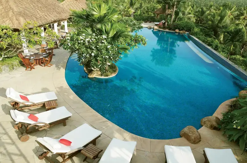 Infinity swimming pool with sun loungers overlooking the landscape at Taj Green Cove Resort Kovalam