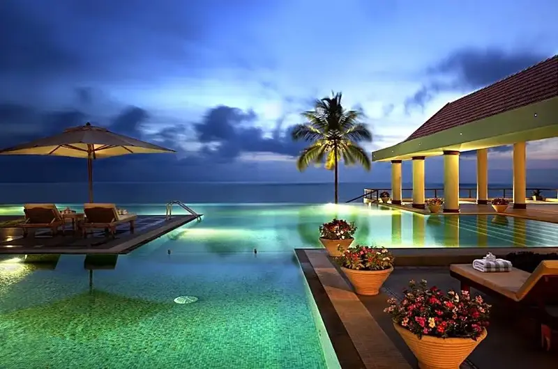 Illuminated outdoor beachfront dining deck and lounge at night in The Leela Kovalam
