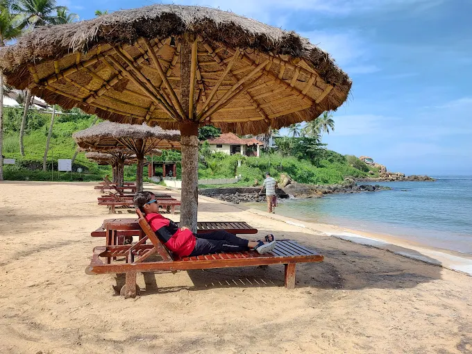 Private beach lounge chairs and sun umbrella setup for guests at The Leela Kovalam