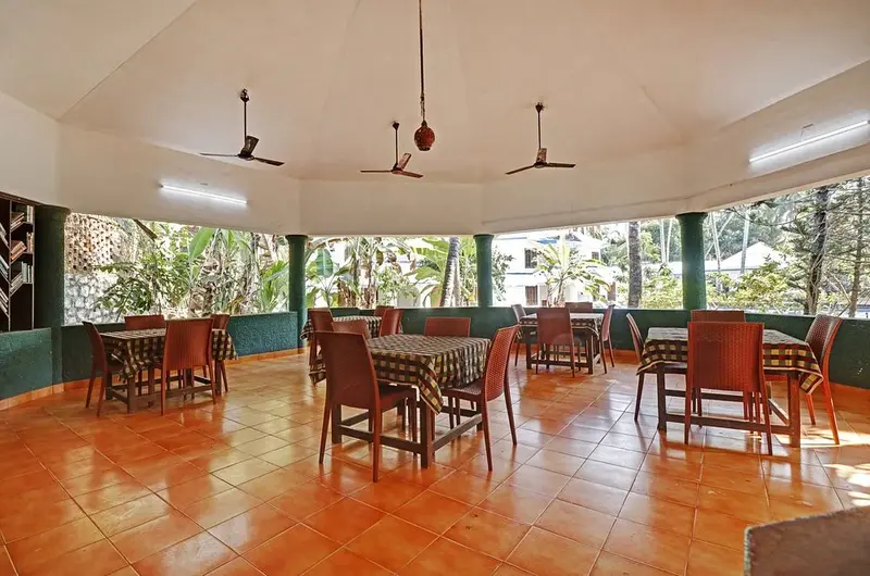 Spacious in house restaurant and dining area with wooden chairs at Treebo Trend Linchu Ayur Resort