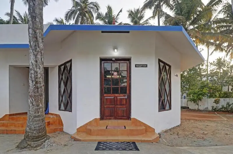 White heritage cottage exterior surrounded by coconut trees at Treebo Trend Linchu Ayur Resort Kovalam