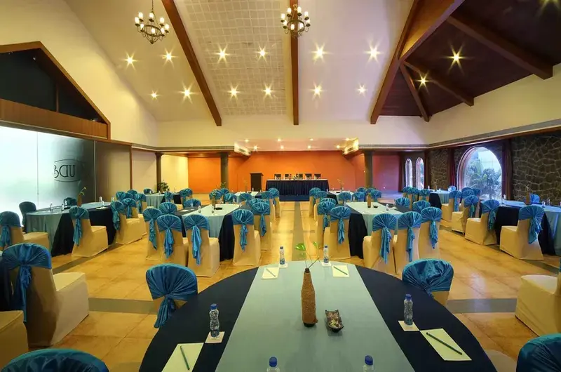 Modern corporate conference hall setup with rows of tables and chairs at Uday Samudra Beach Hotel.