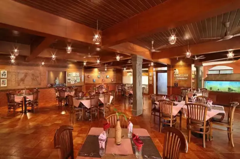 Elegant indoor multi-cuisine family restaurant layout featuring premium wooden seating at Uday Samudra Kovalam.