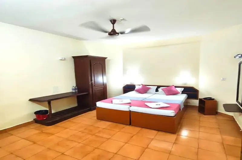 Comfortable family suite room layout with tiled flooring and wooden furniture at Hotel Thushara Kovalam.