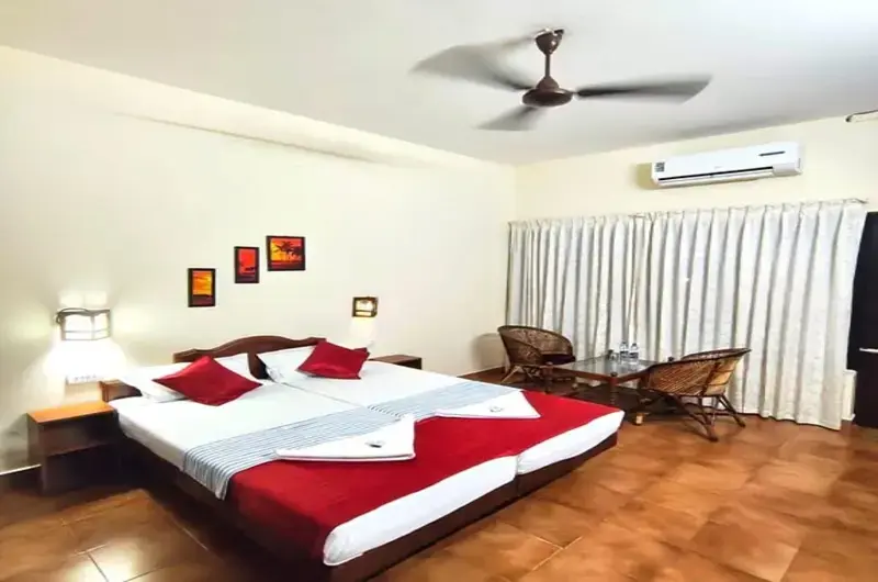 Clean air-conditioned double bedroom accommodation with red bedding accents at Hotel Thushara Kovalam.