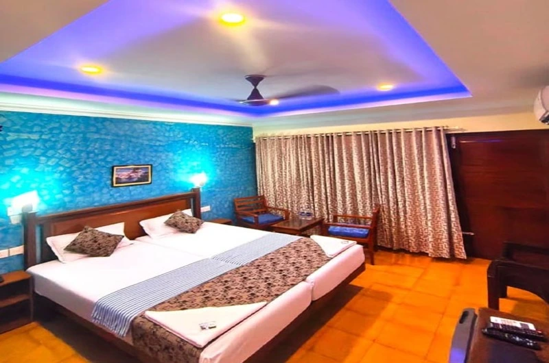 Premium guest bedroom interior featuring elegant blue recessed ceiling lighting at Hotel Thushara Kovalam.