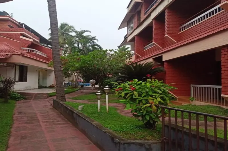 Terracotta red exterior building and stone walkway at Hotel Thushara Kovalam.