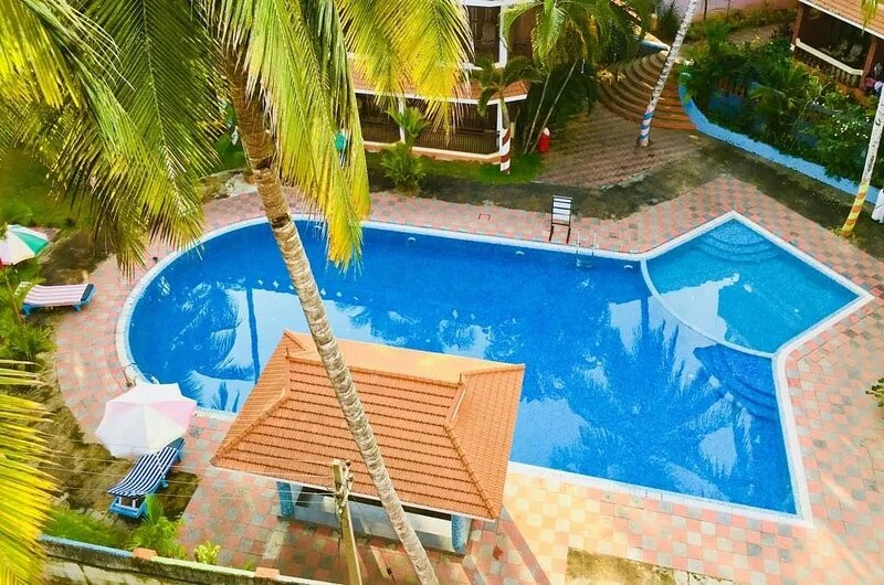 High-angle view of the swimming pool and poolside relaxation gazebo at Jasmine Palace Kovalam.