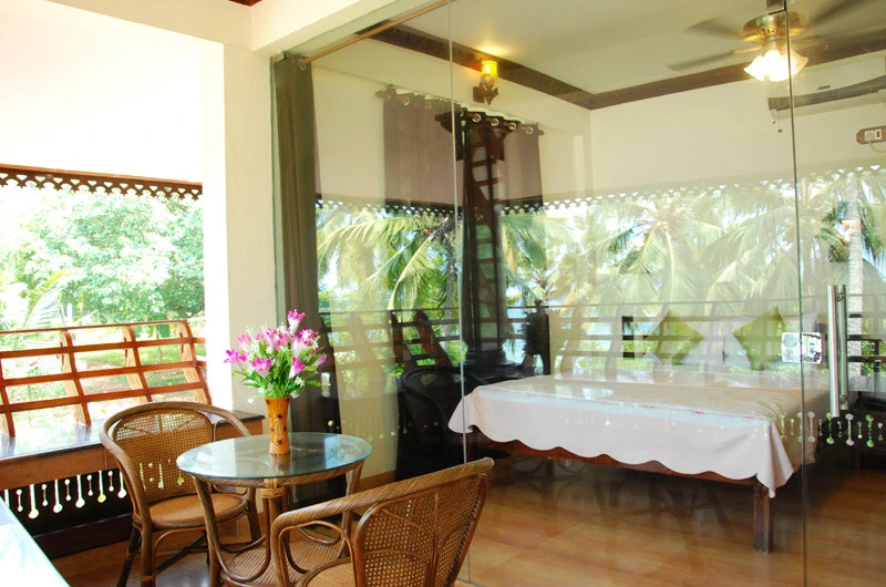 Deluxe guest room layout featuring a wooden sit-out lounge area at Kovalam Beach Hotel.