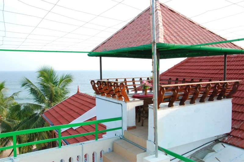 Open-air rooftop terrace and traditional tiled gazebo overlooking the ocean at Kovalam Beach Hotel.