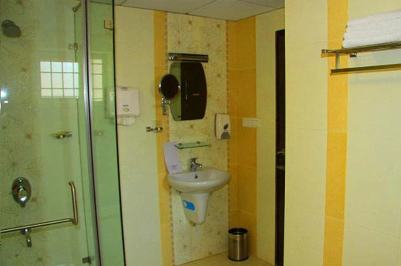 Contemporary attached guest bathroom layout with a glass partitioned shower at La Promenade Hotel Kovalam.