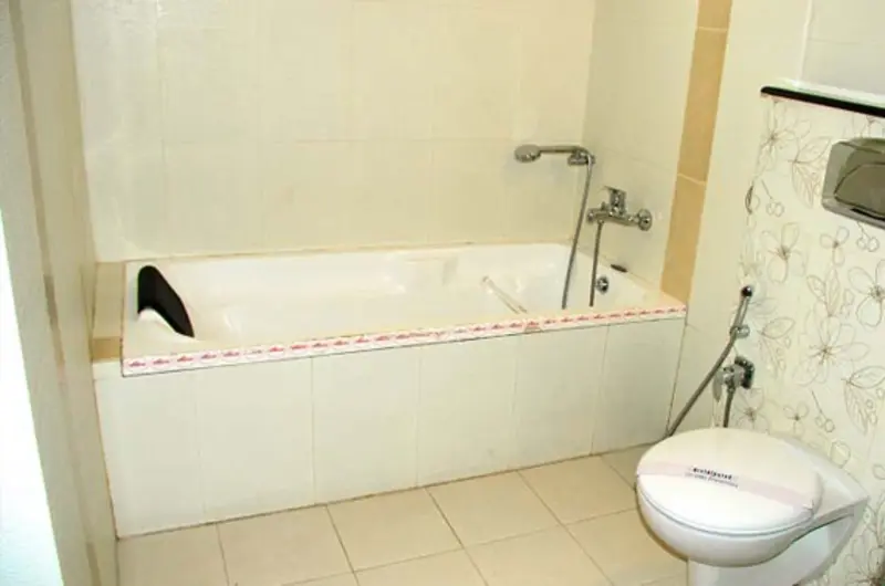Clean attached bathroom interior featuring a modern bathtub and white ceramic sink at La Promenade Hotel Kovalam.