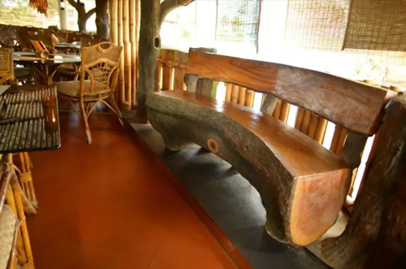 Indoor restaurant window seating with rustic wooden benches at La Promenade Hotel Kovalam.