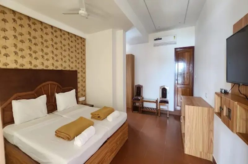 Deluxe guest room interior featuring a decorative wooden accent headboard wall at Hotel Marine Palace Kovalam.